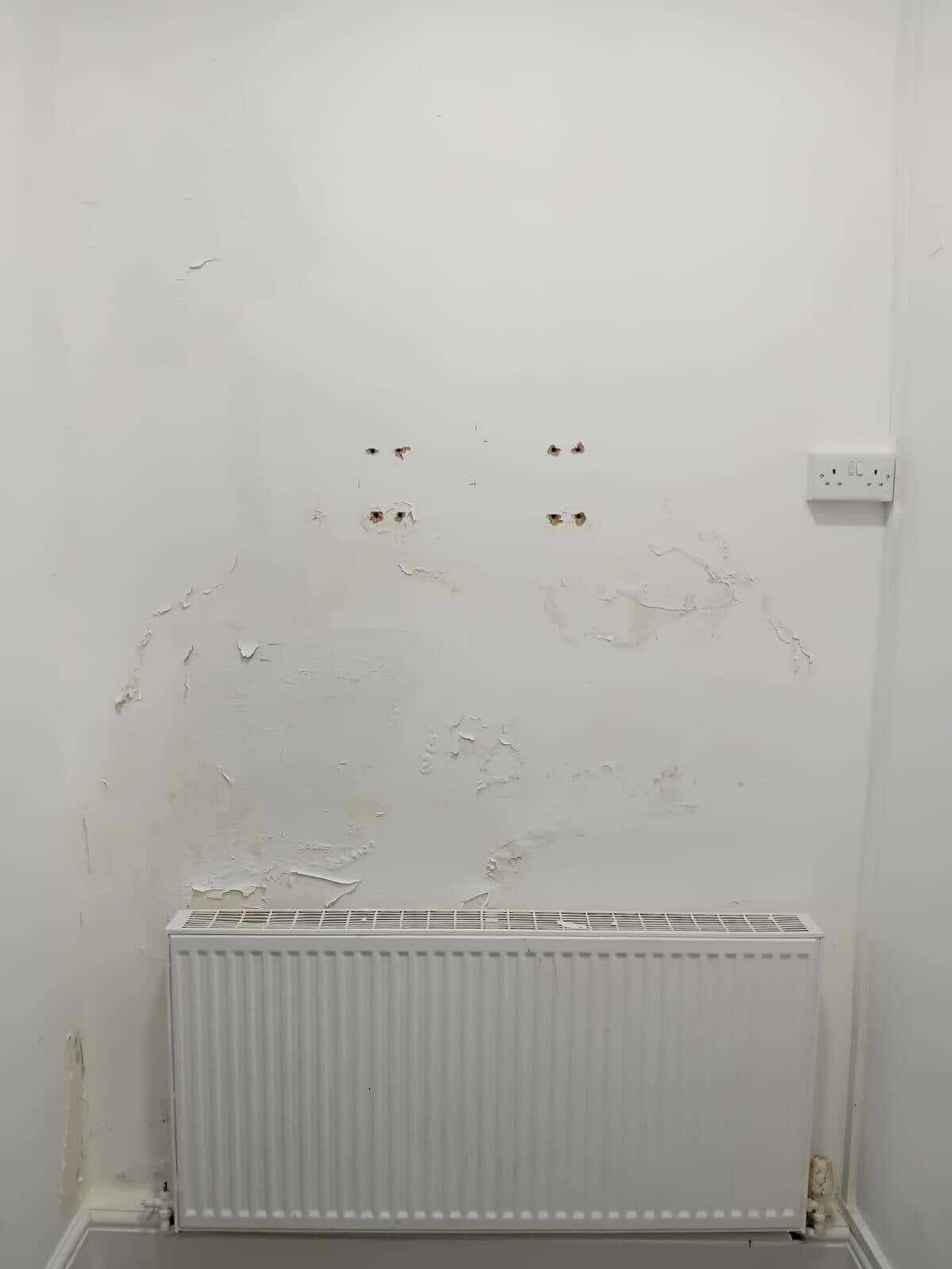 Before: wall above a radiator with flaking paint and stained patches