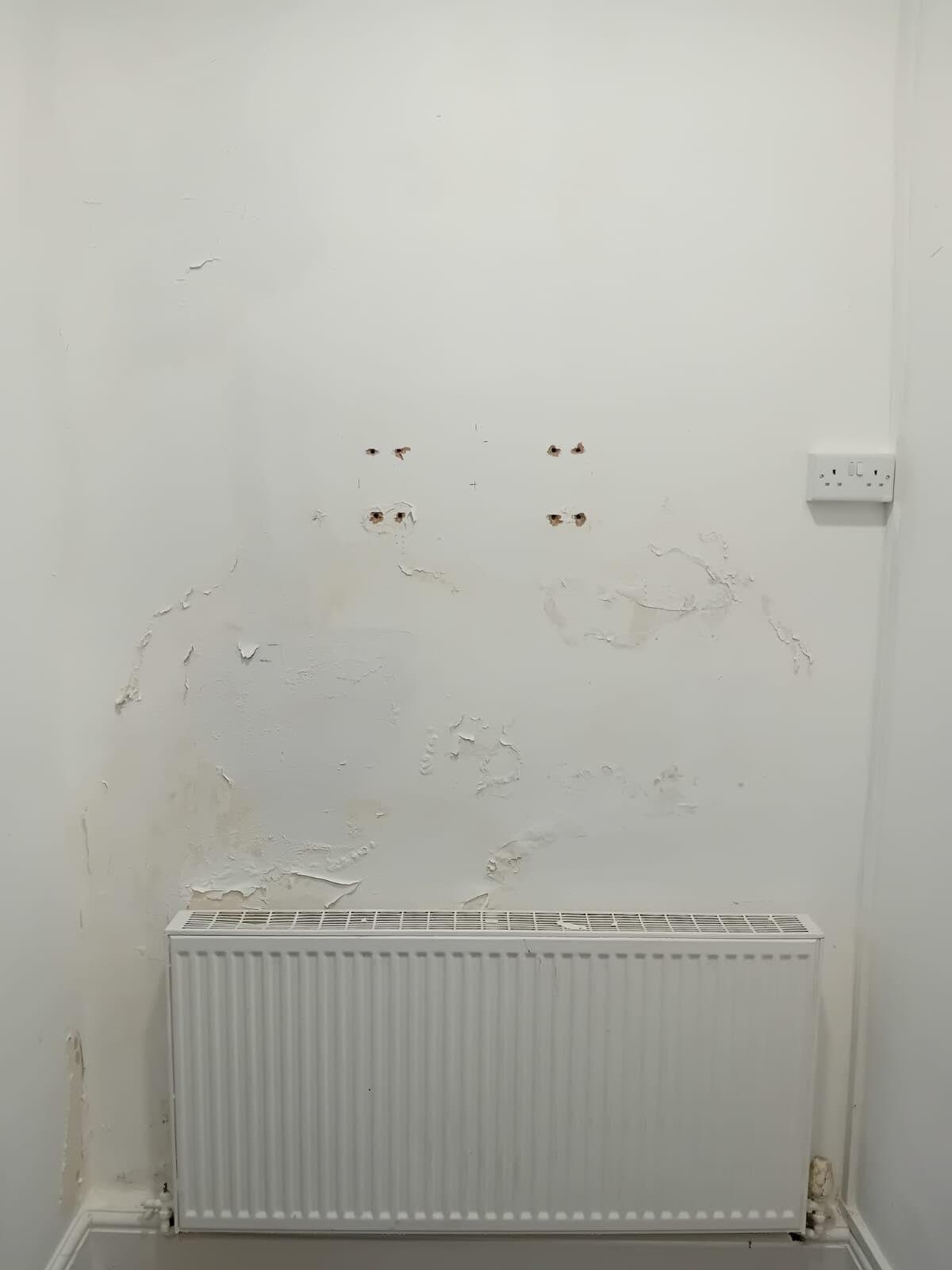 Before: wall above a radiator with flaking paint and stained patches