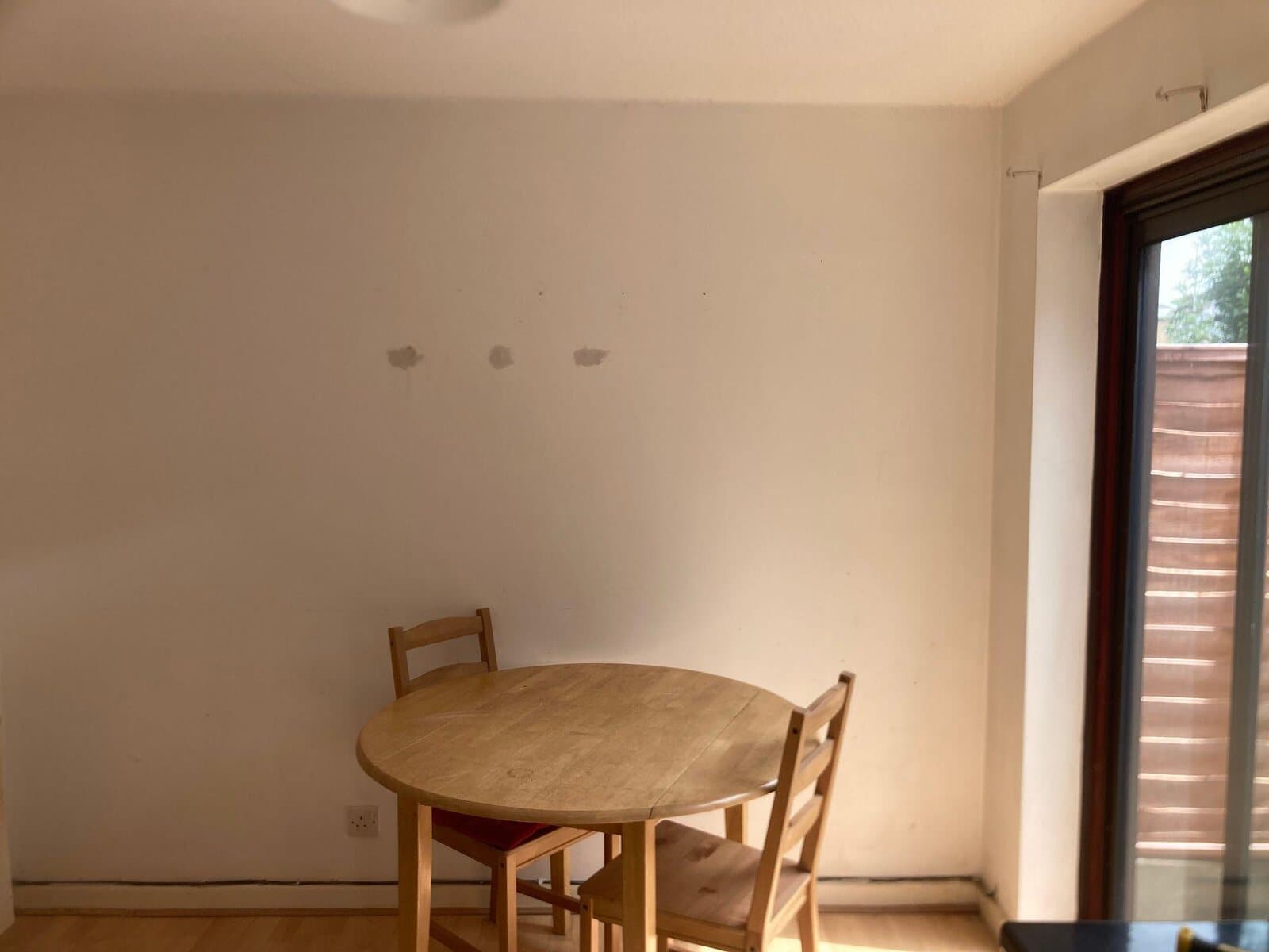 Before: dining room wall with fixing holes above a round table