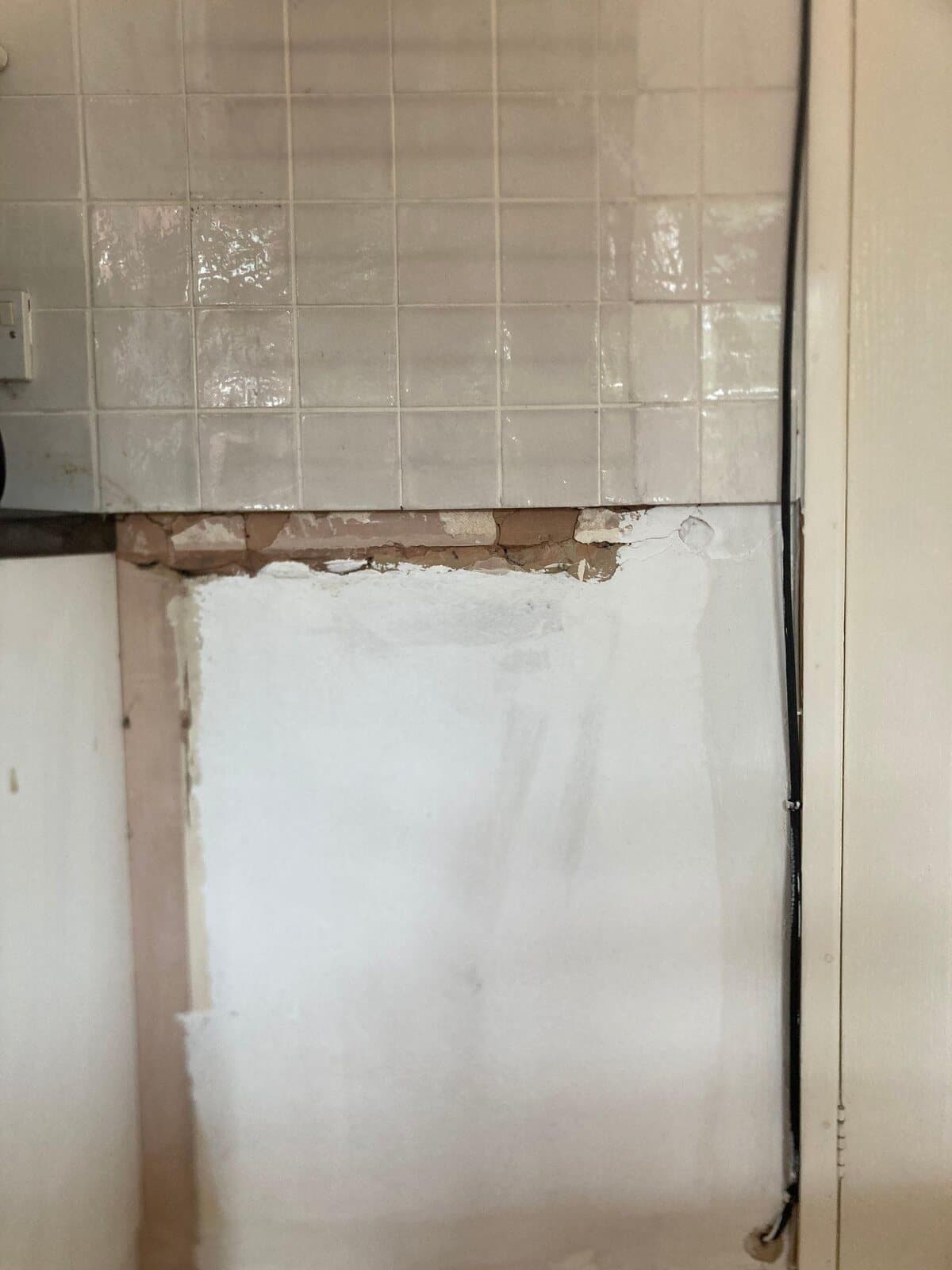 Before: patched bare wall and exposed timber under a row of tiles