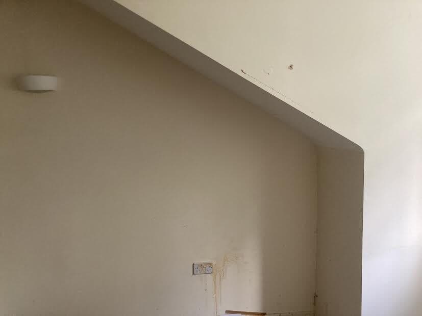 Before: alcove under the stairs with marks and stains on the wall