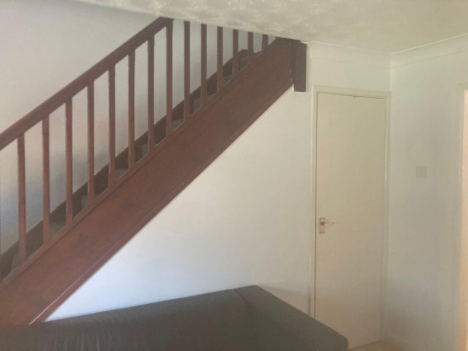 Finished stairwell with white walls under a timber staircase